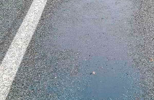 Gros plan sur une rue dont une partie appara&icirc;t tr&egrave;s lisse et brillante, &eacute;voquant un miroir.